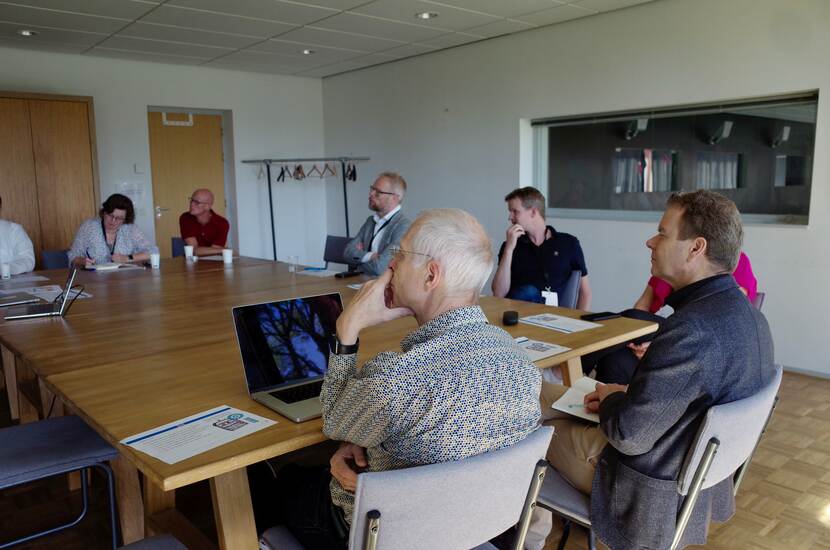 Ketenarchitecten zitten met elkaar aan tafel en luisteren bij een sessie